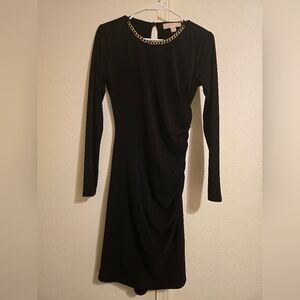 Michael Kors black knee-length dress with gold chain accessories.